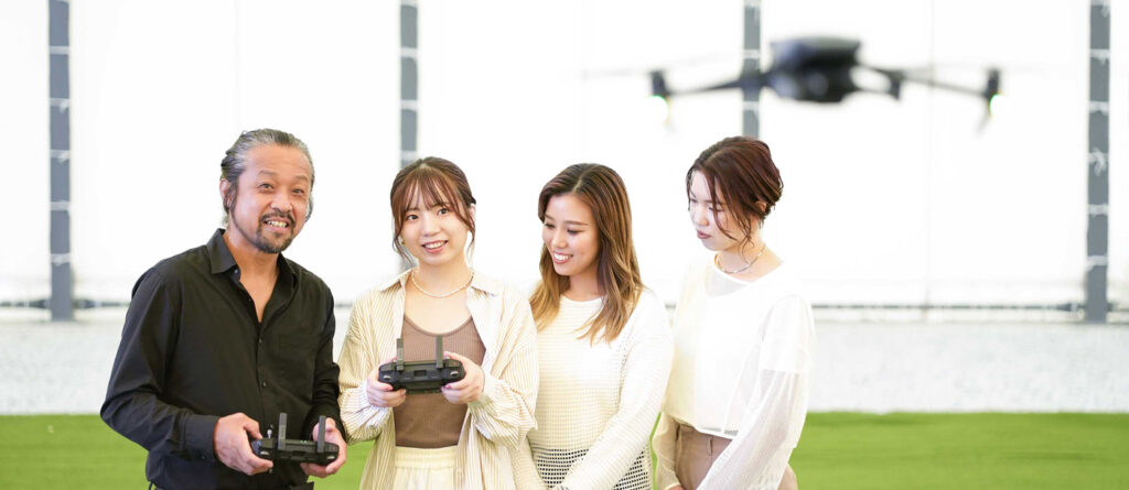 ドローンを飛行させる受講生とエミュドローンアカデミーのインストラクター